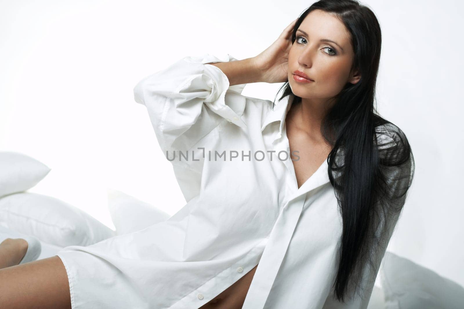 Beautiful brunette woman on bed, wearing white large casual shirt