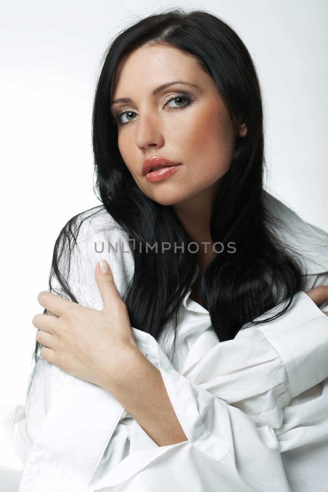 Beautiful brunette woman on bed, wearing white large casual shirt