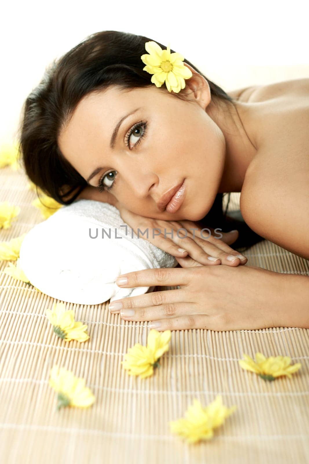 Portrait of Fresh and Beautiful brunette woman laying on bamboo mat around yellow flowers
