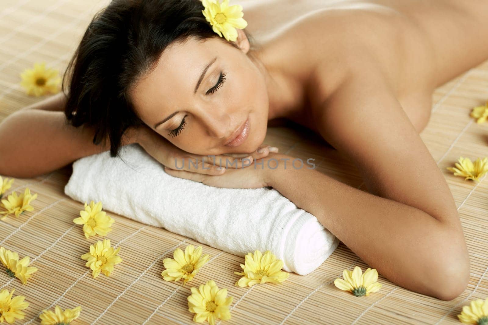 Portrait of Fresh and Beautiful brunette woman laying on bamboo mat around yellow flowers