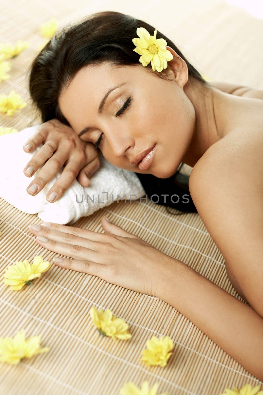 Portrait of Fresh and Beautiful brunette woman laying on bamboo mat around yellow flowers