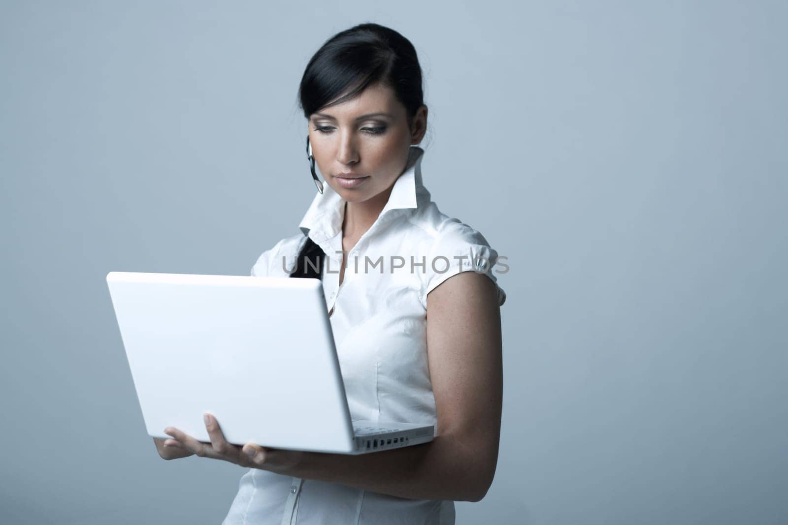 Beautiful and sexy brunette business woman with laptop computer. She is isolated on clear background