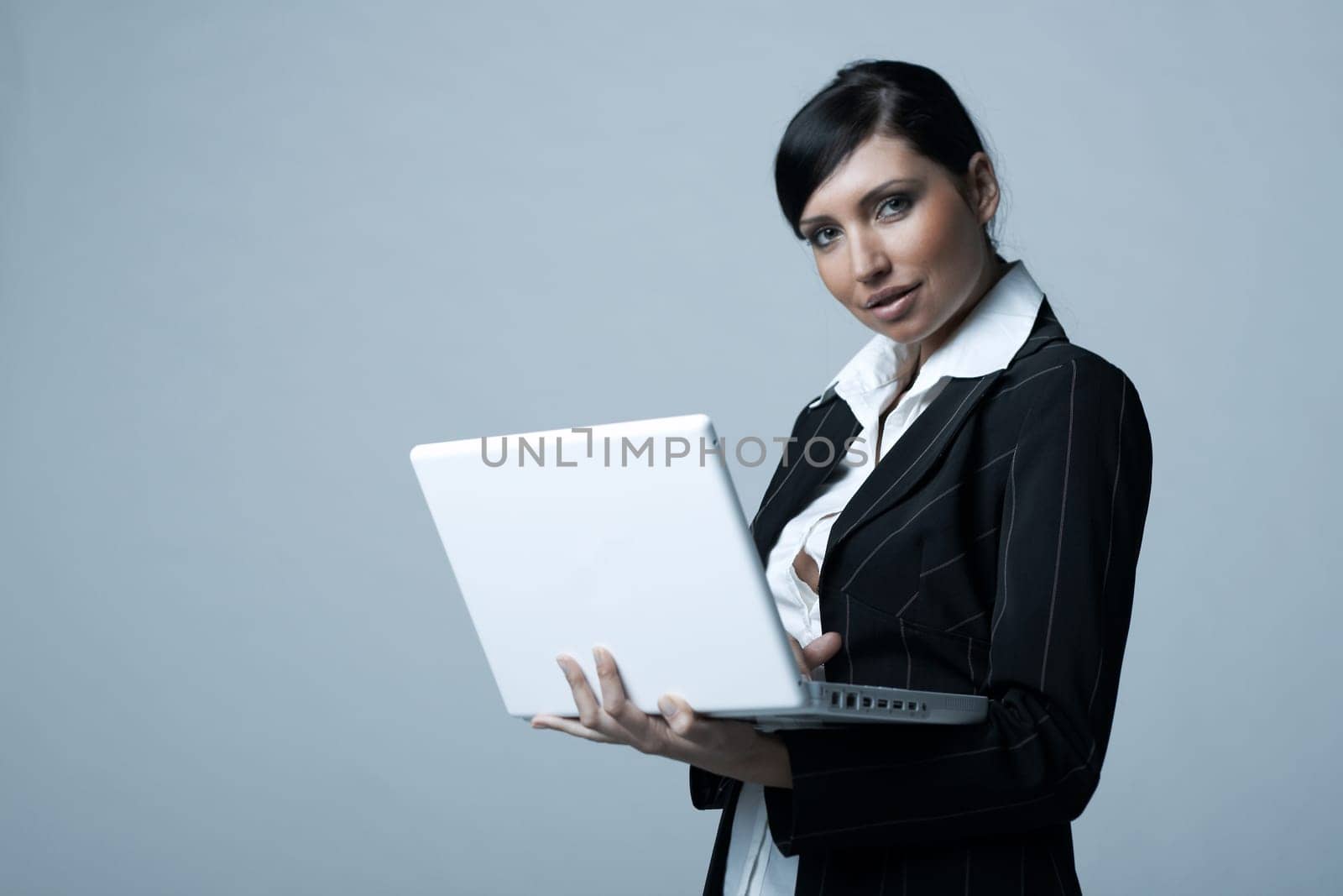 Beautiful and sexy brunette business woman with laptop computer. She is isolated on clear background