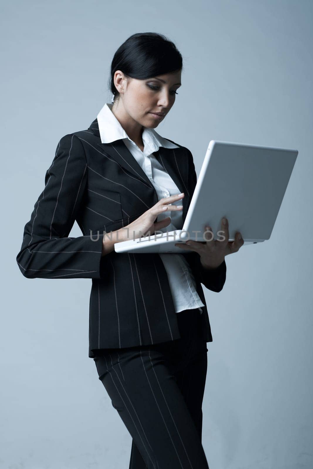 Beautiful and sexy brunette business woman with laptop computer. She is isolated on clear background