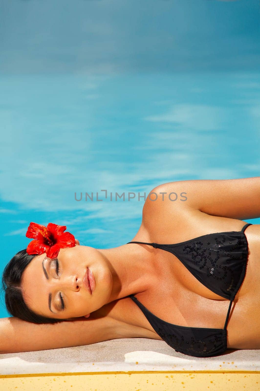 Beautiful young Sexy woman laying in bikini during sunbath next to swimming pool