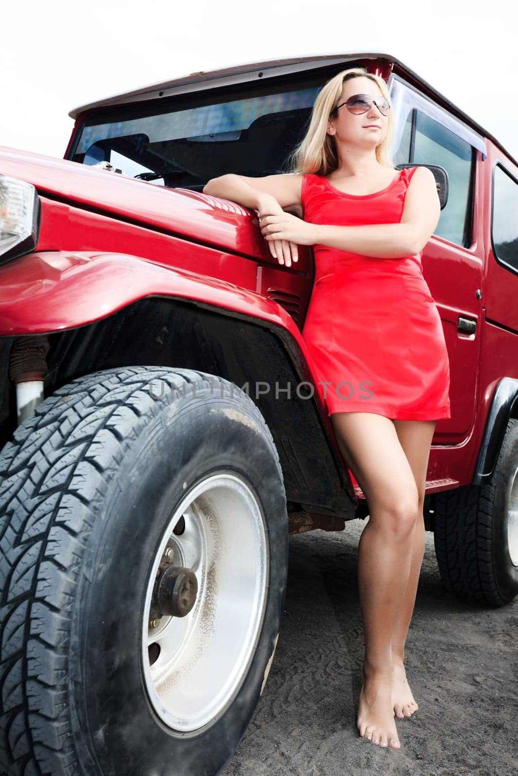 Beautiful model posing near car in red dress
