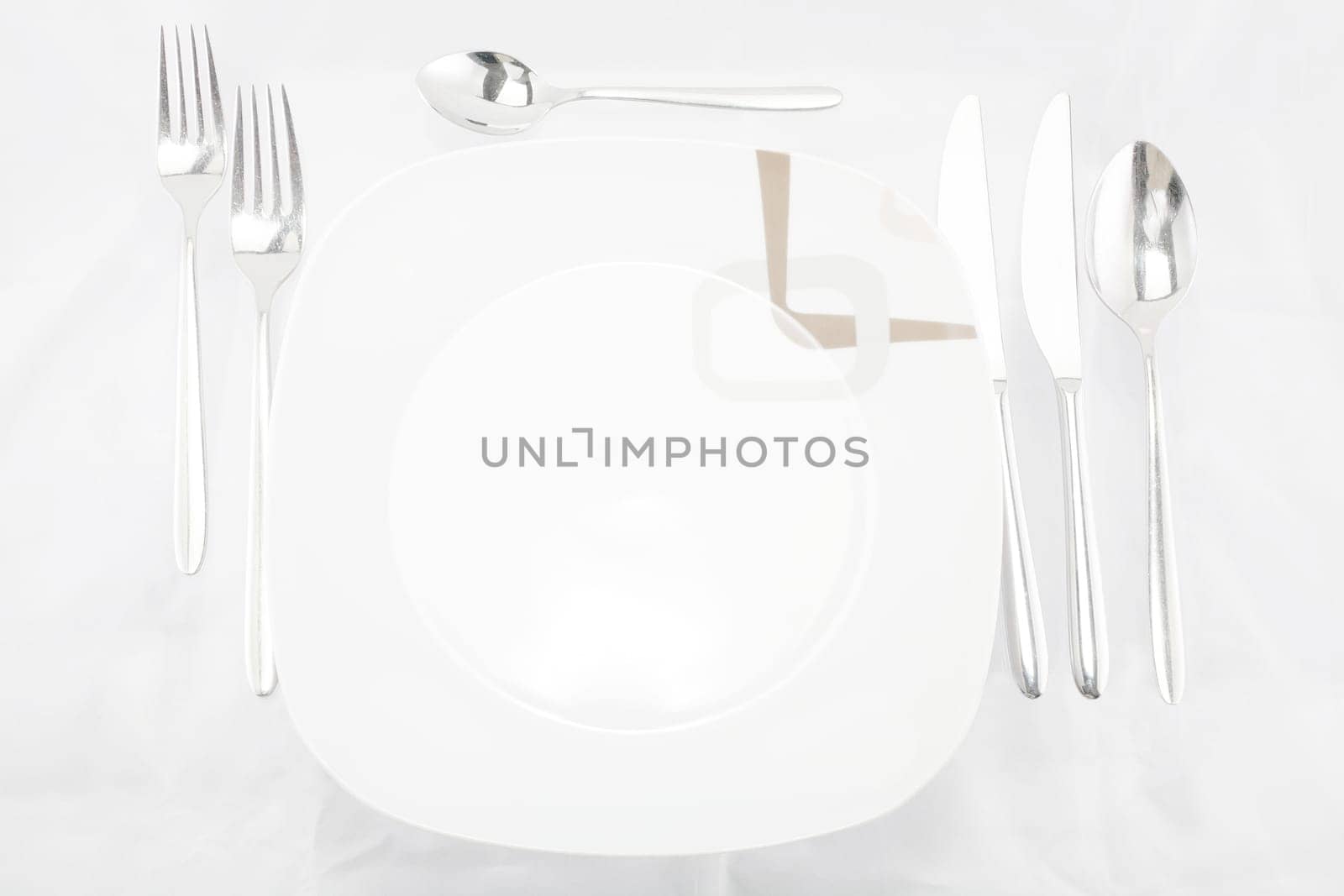 Plates with a silver fork, spoon, dessert spoon and a knife