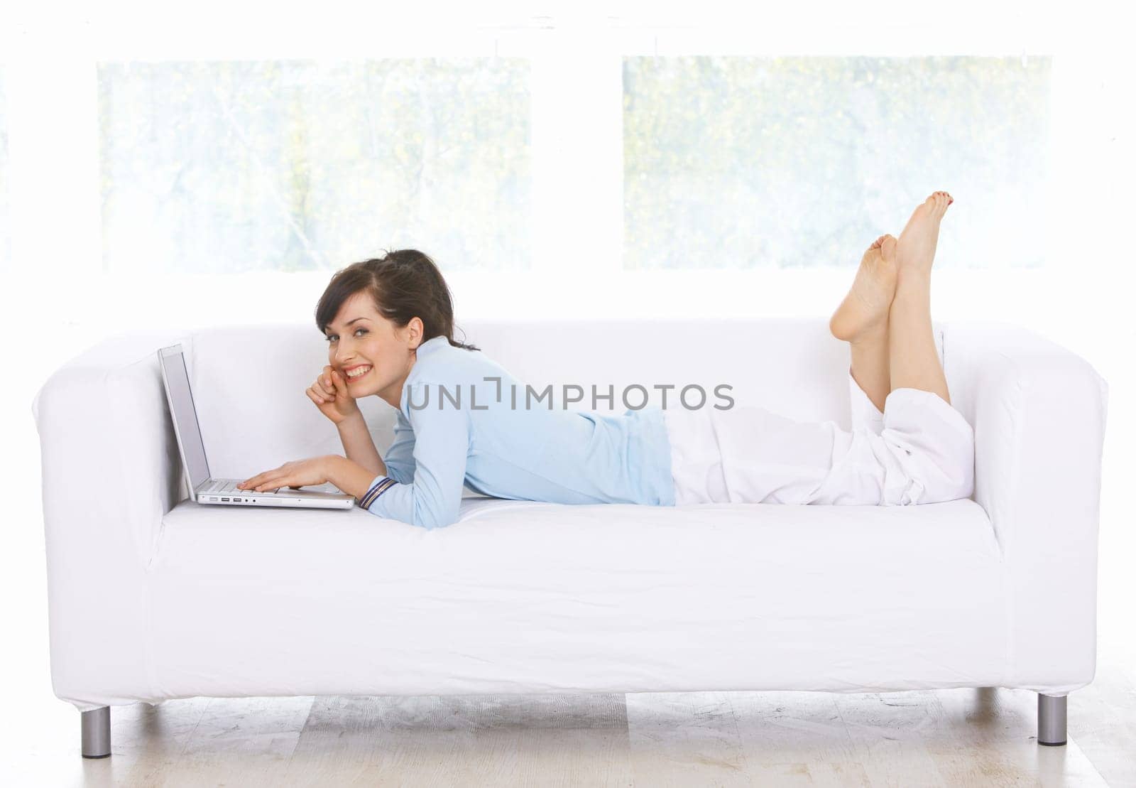 Young woman is on couch and working on laptop