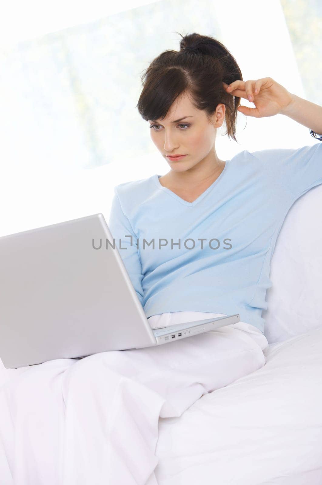 Young woman is on couch and working on laptop