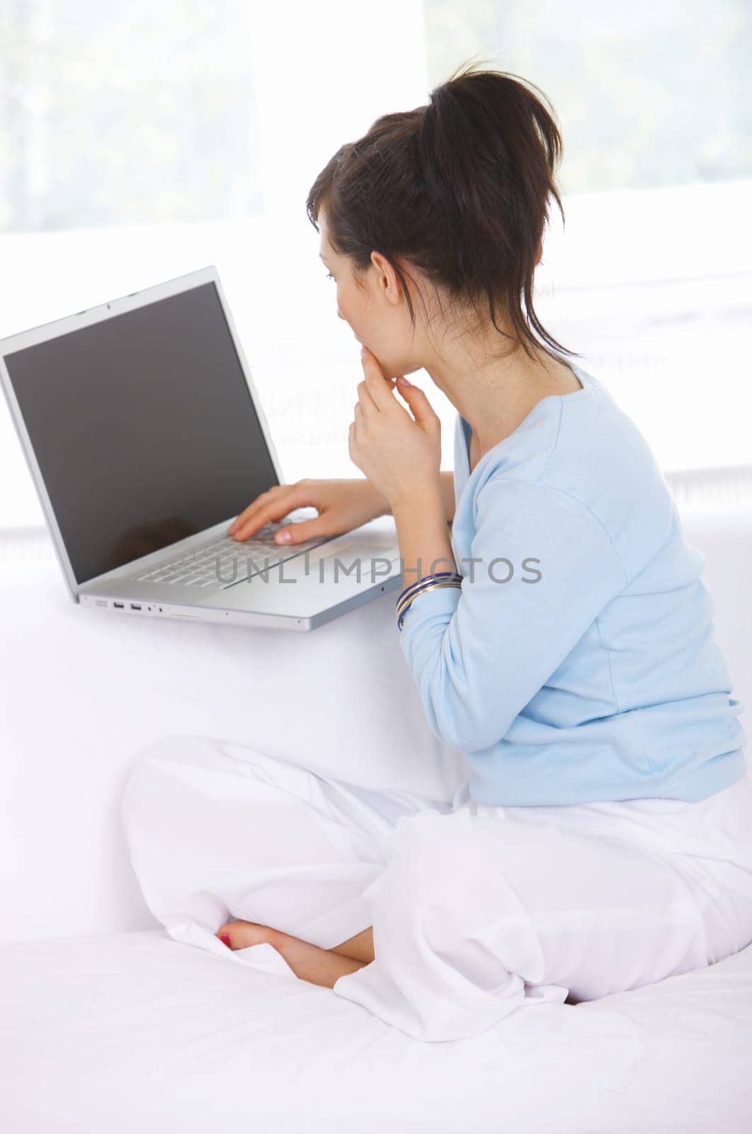 Young woman is on couch and working on laptop
