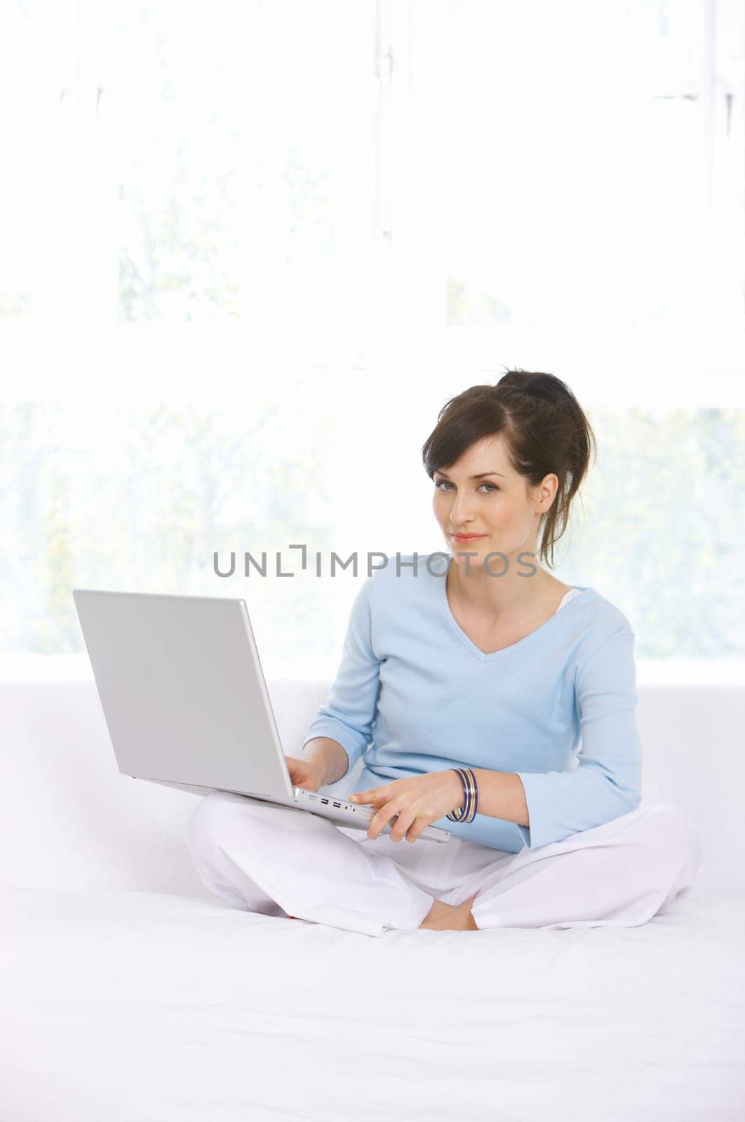Young woman is on couch and working on laptop
