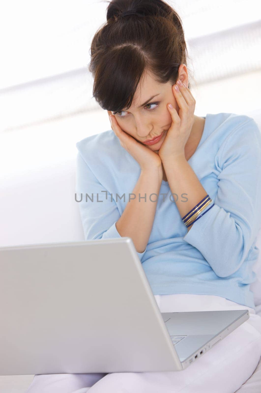Young woman is on couch and working on laptop