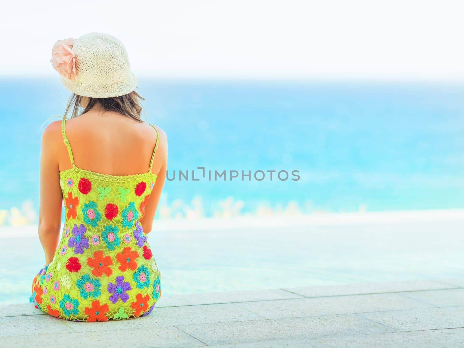 Rear view of woman sitting on the edge of swiming pool