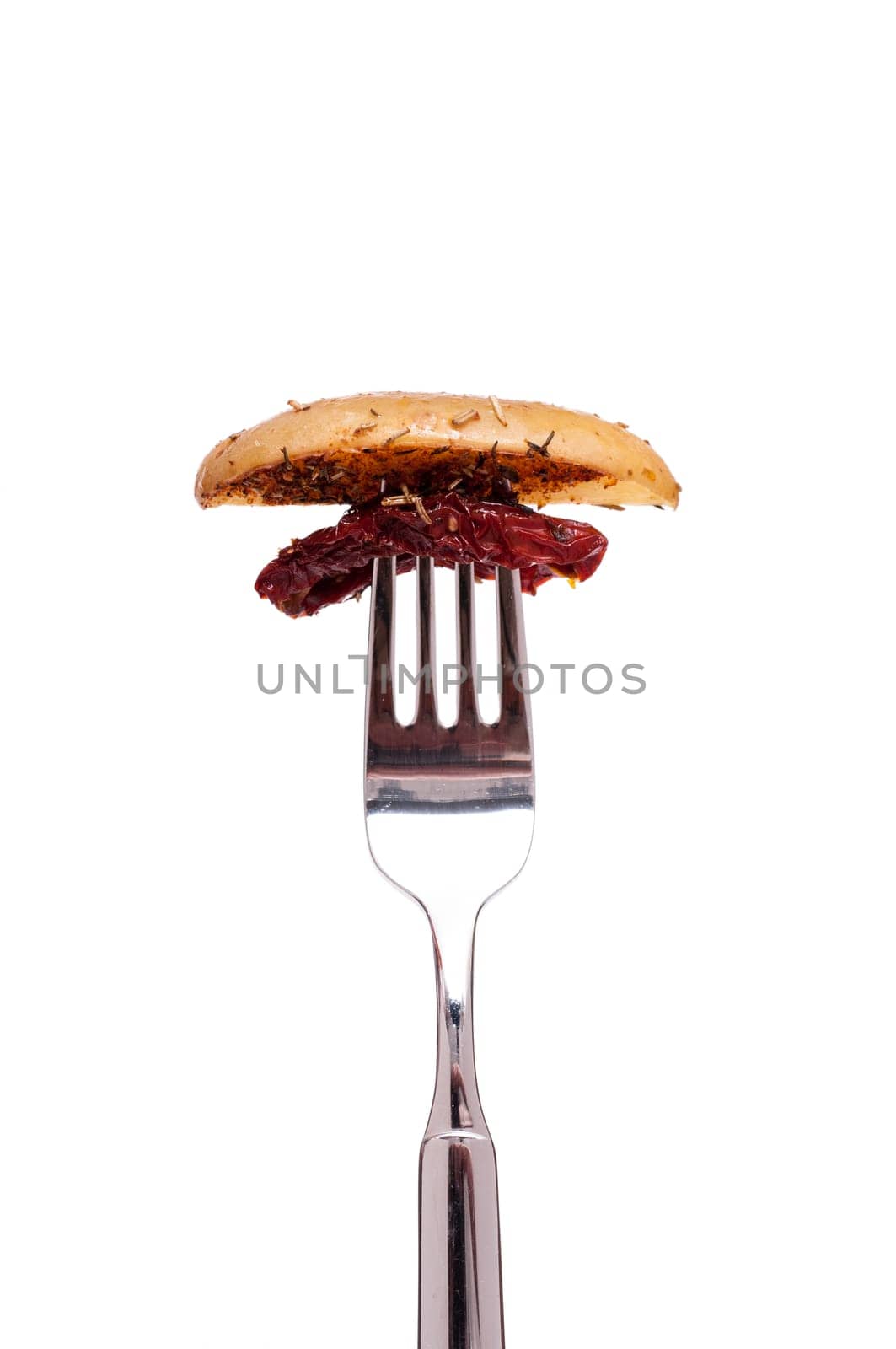 Fried potato and dried tomato on a fork