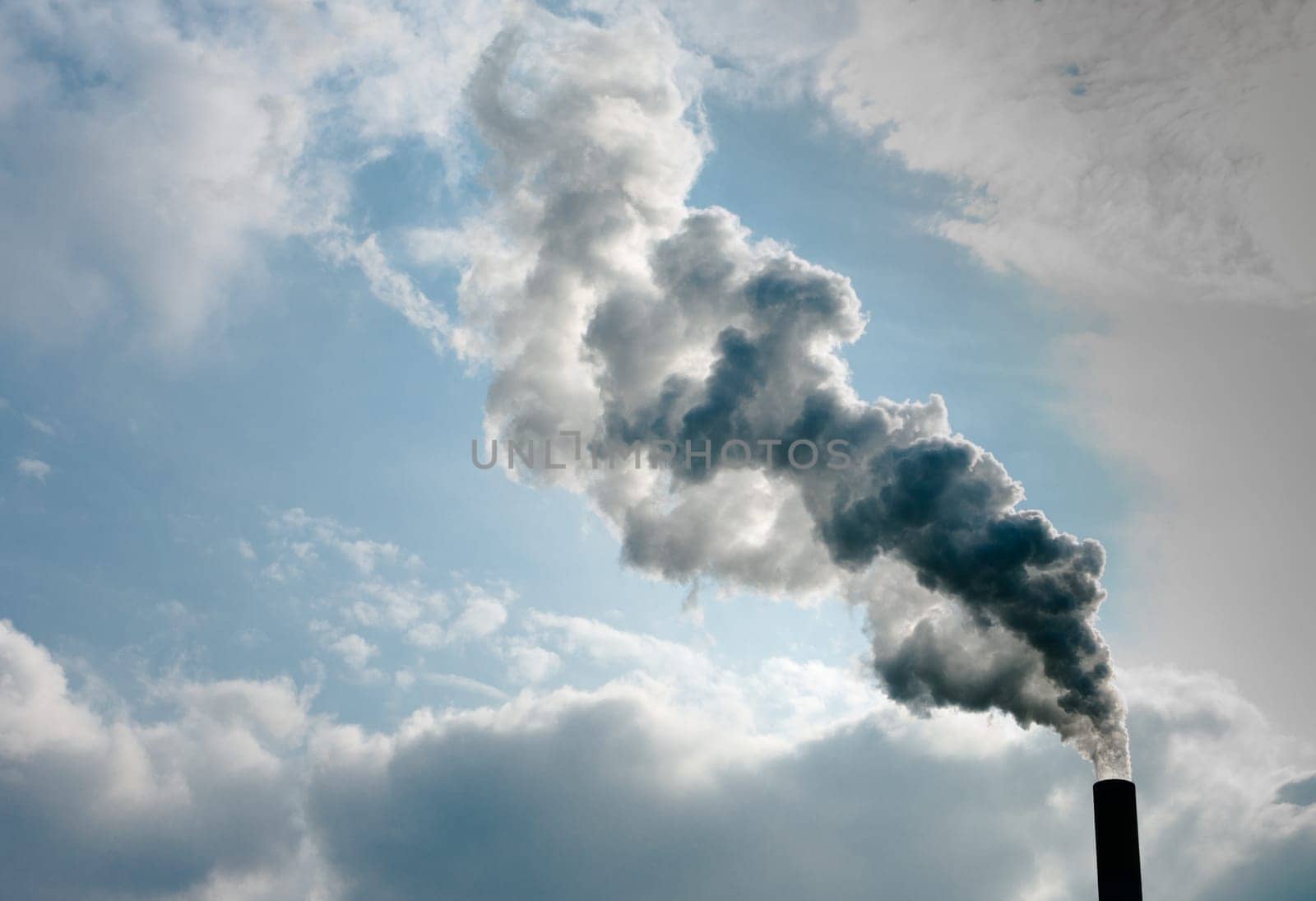 smoking chimney of a power plant against a blue sky