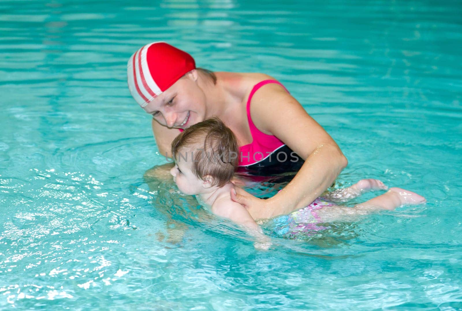 Young family with baby having fun in the swimming pool