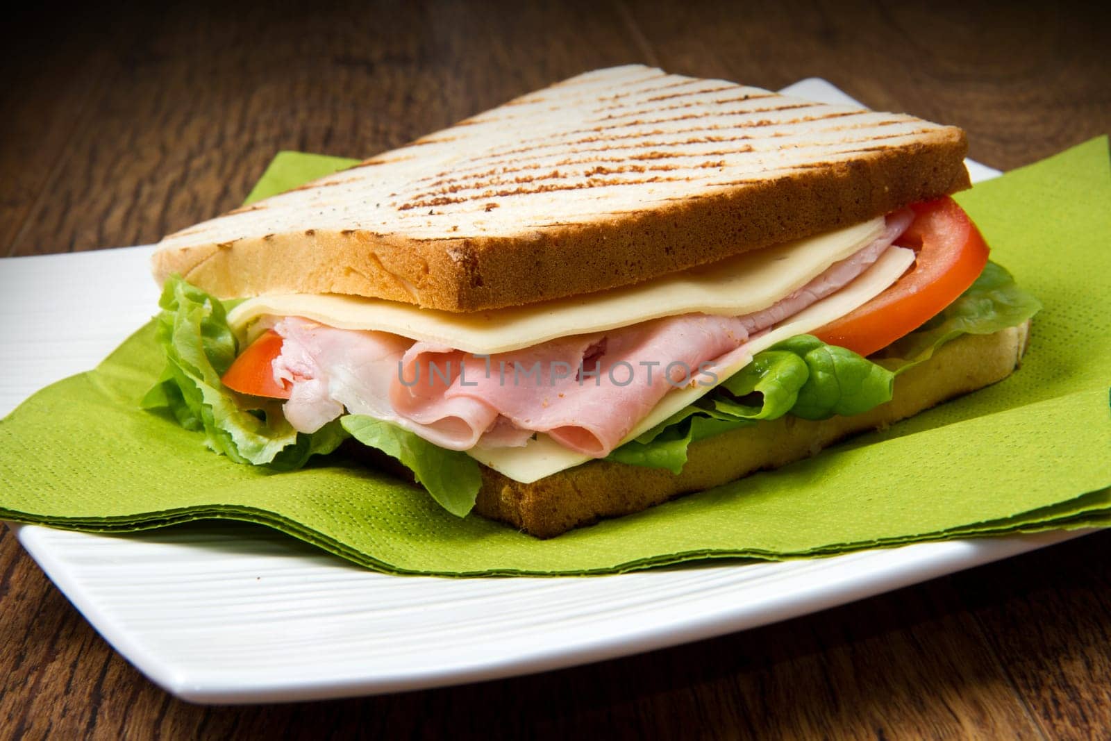 big sandwich with ham, cheese, tomatoes and salad on toasted bread