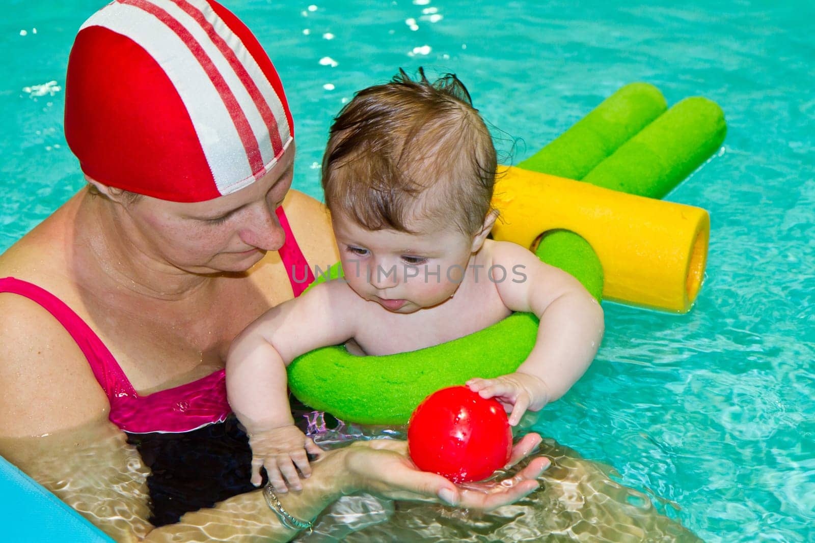 Young family with baby having fun in the swimming pool
