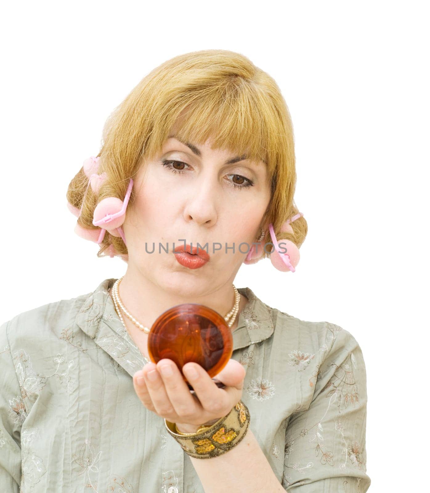 Housewife putting makeups, getting ready to go party, wearing hair rollers and looking into the mirror. Isolated over white background.