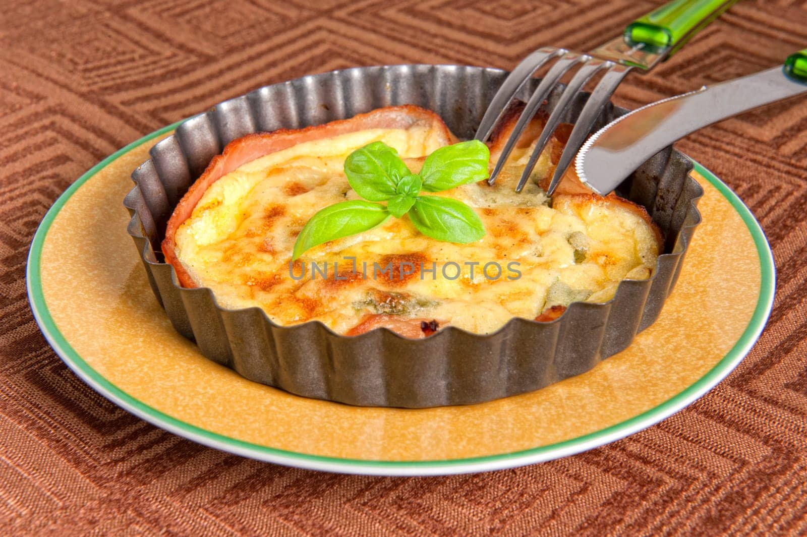 Eggs and bacon tart with basil leaves