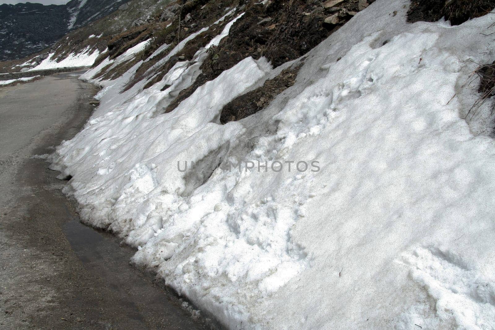 Ice on roadside melts and slips down as water at lower end