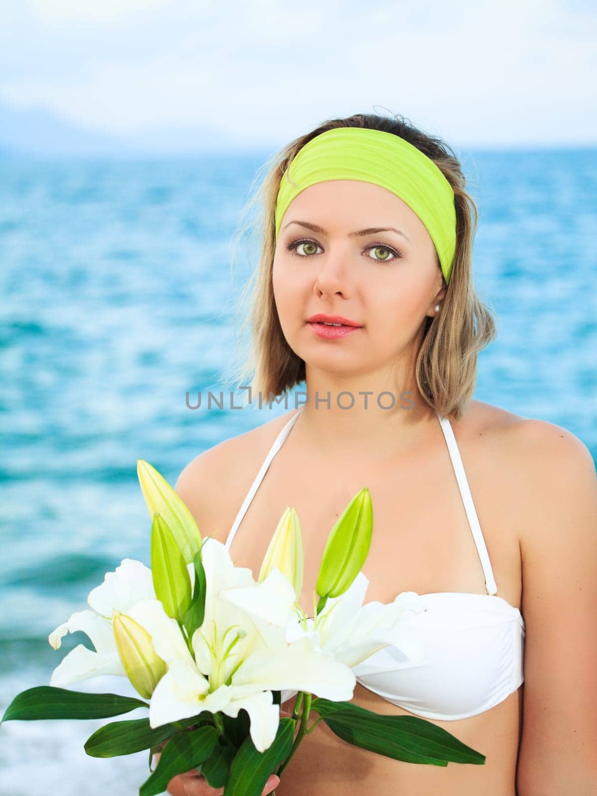 Beautiful woman near the ocean with flowers