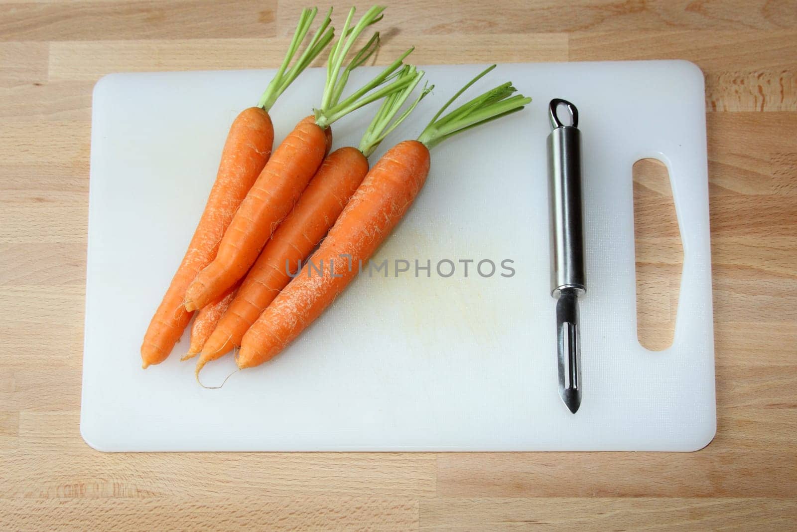 details of carrots on a cutting board with a peeler