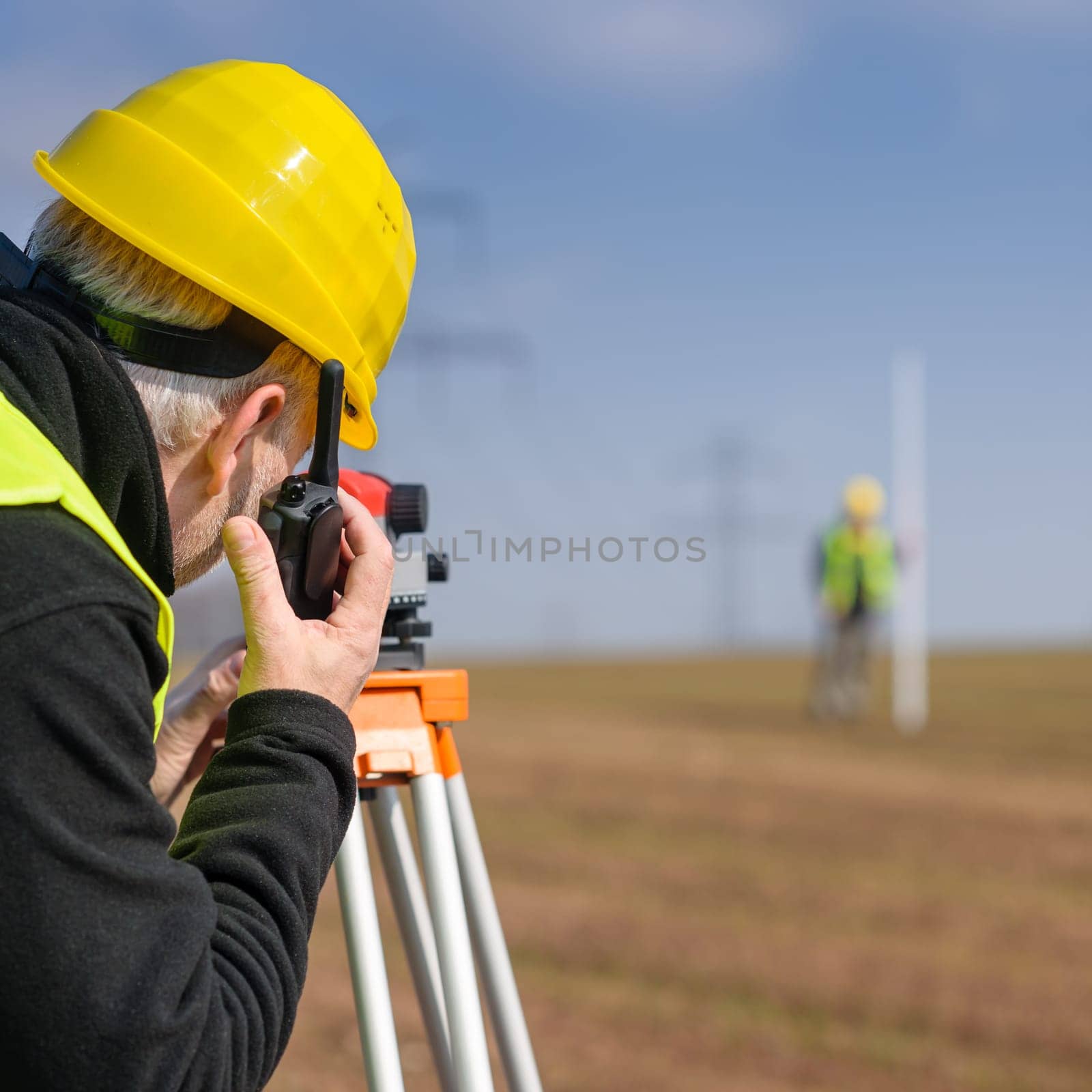 Land surveyors measuring land with tacheometer speaking through transmitter