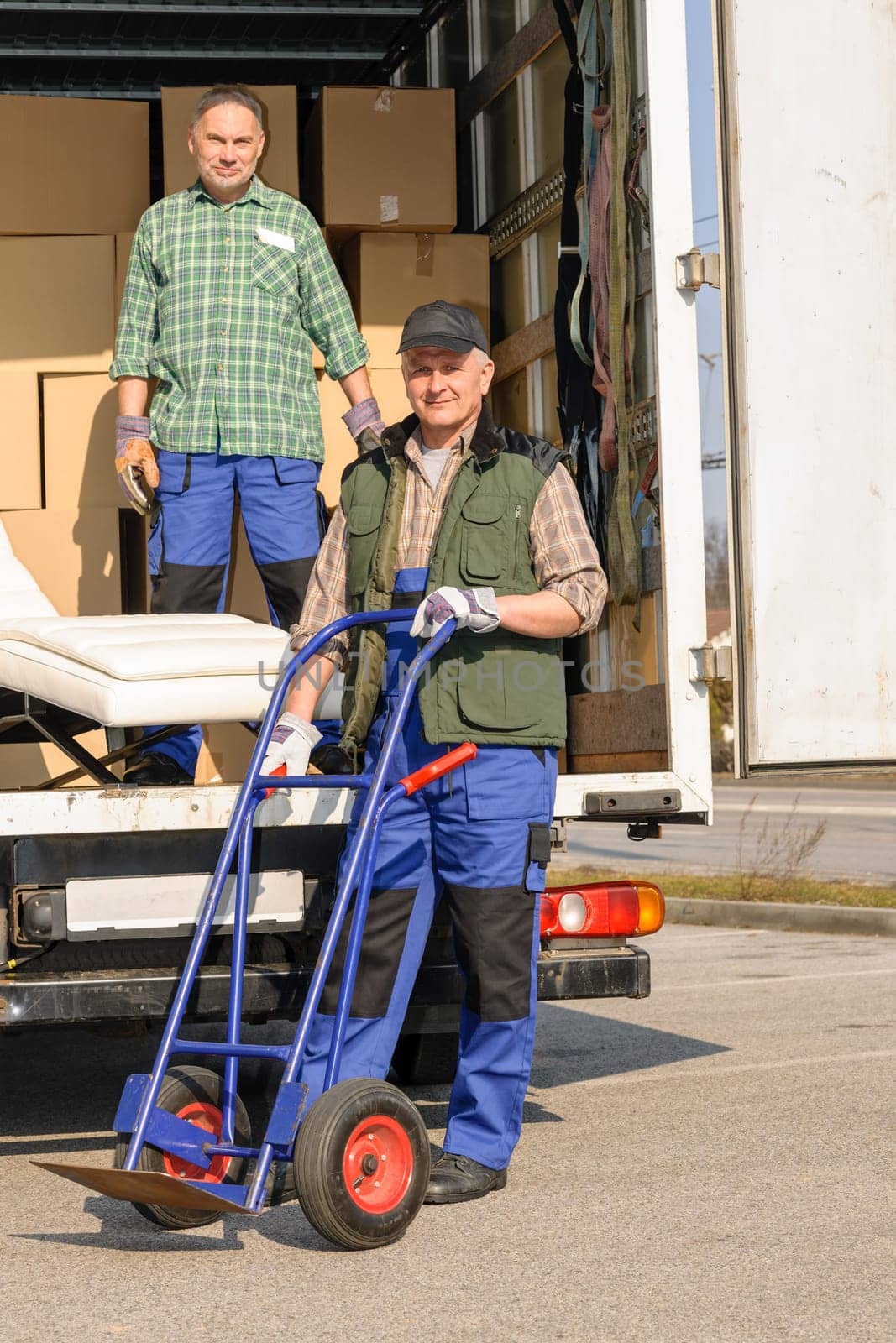 Two movers man loading furniture and boxes from truck vehicle