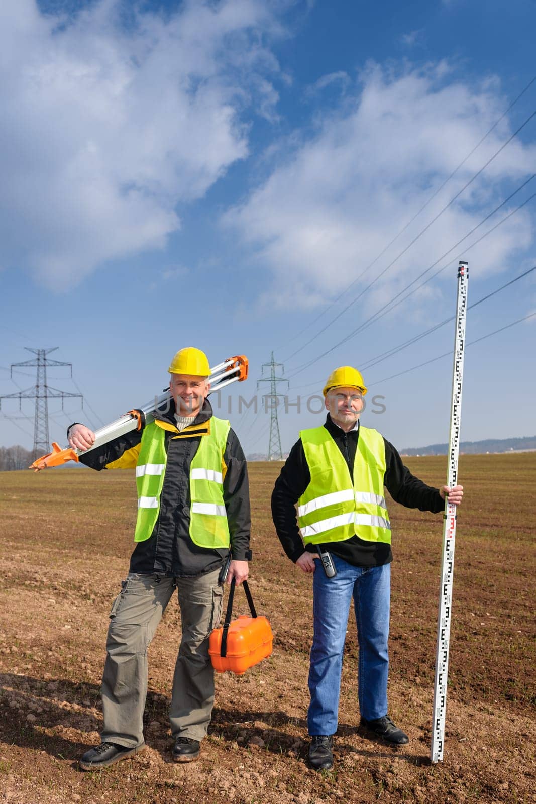 Portrait of two geodesist holding measuring equipment on construction site