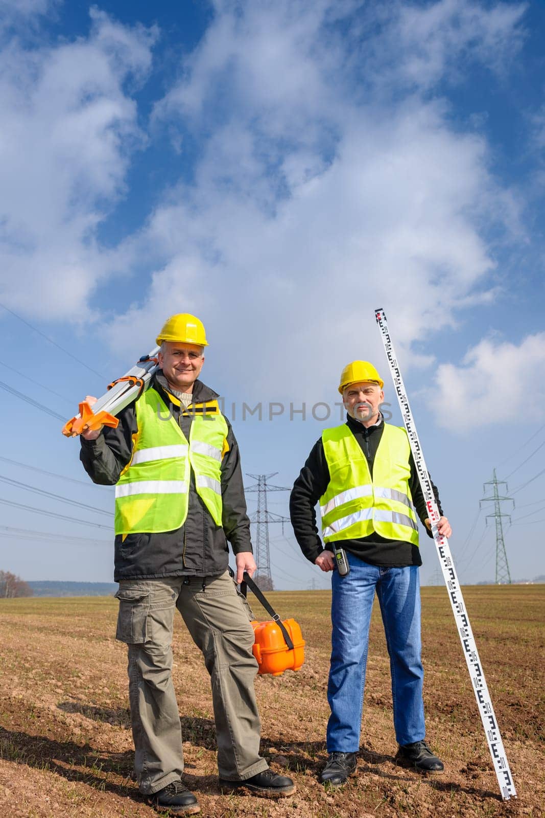 Portrait of two geodesist holding measuring equipment on construction site
