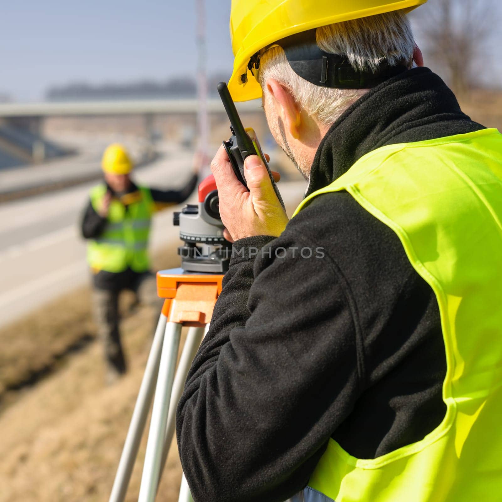 Land surveyors on highway measuring with theodolite