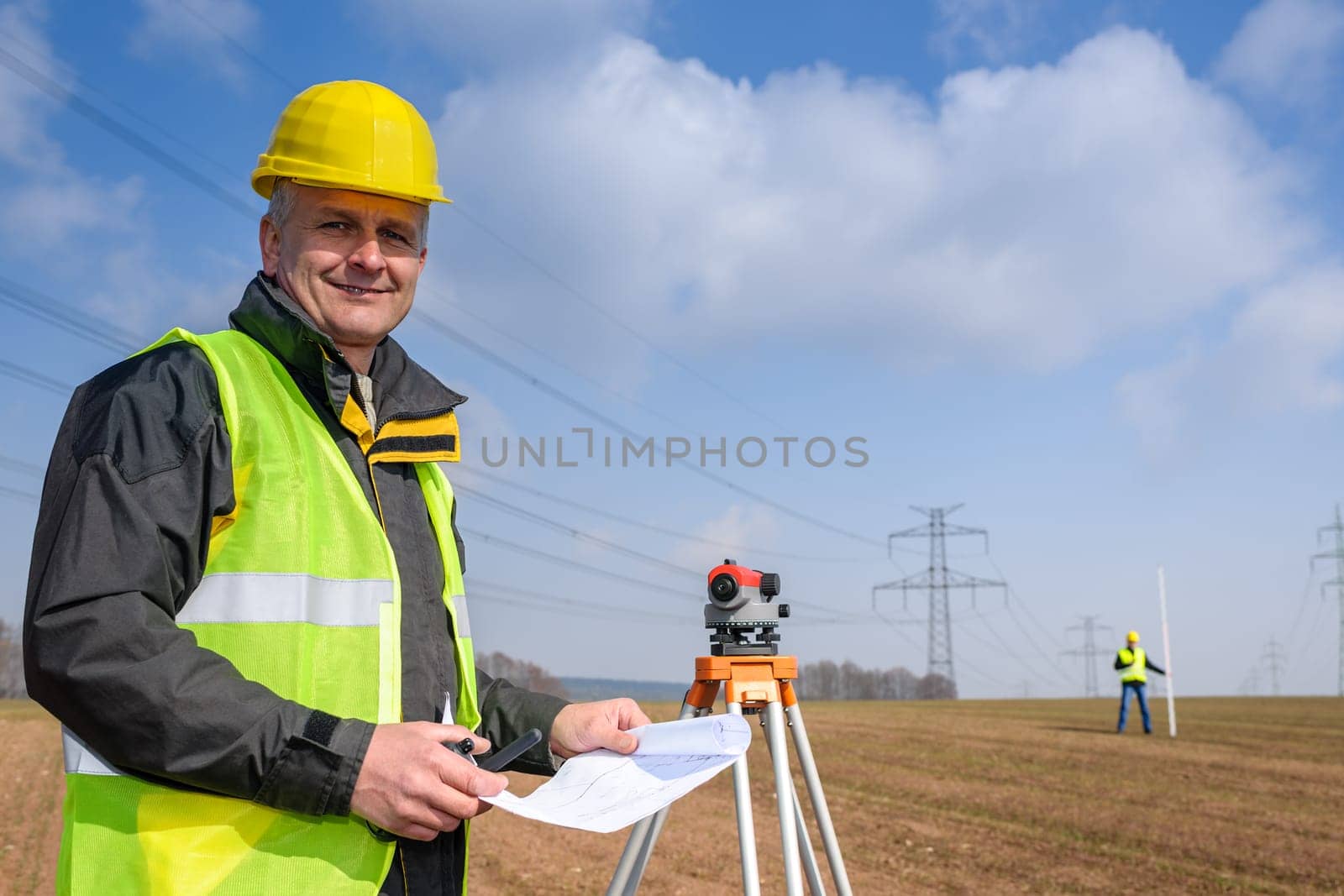Land surveyors measuring with tacheometer wear reflective safety vest