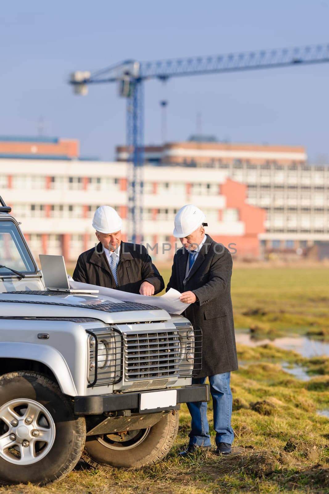 Two architect developers reviewing building plans at construction site