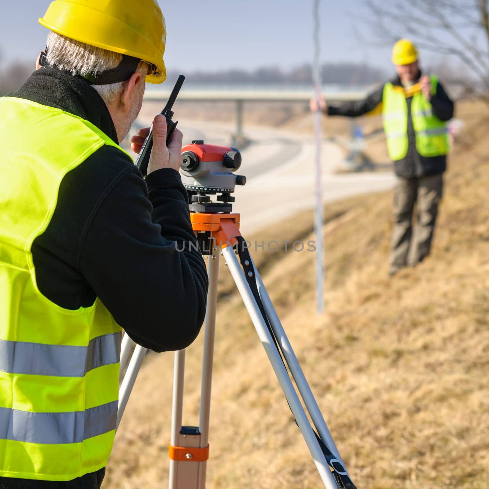 Land surveyors on highway measuring with theodolite