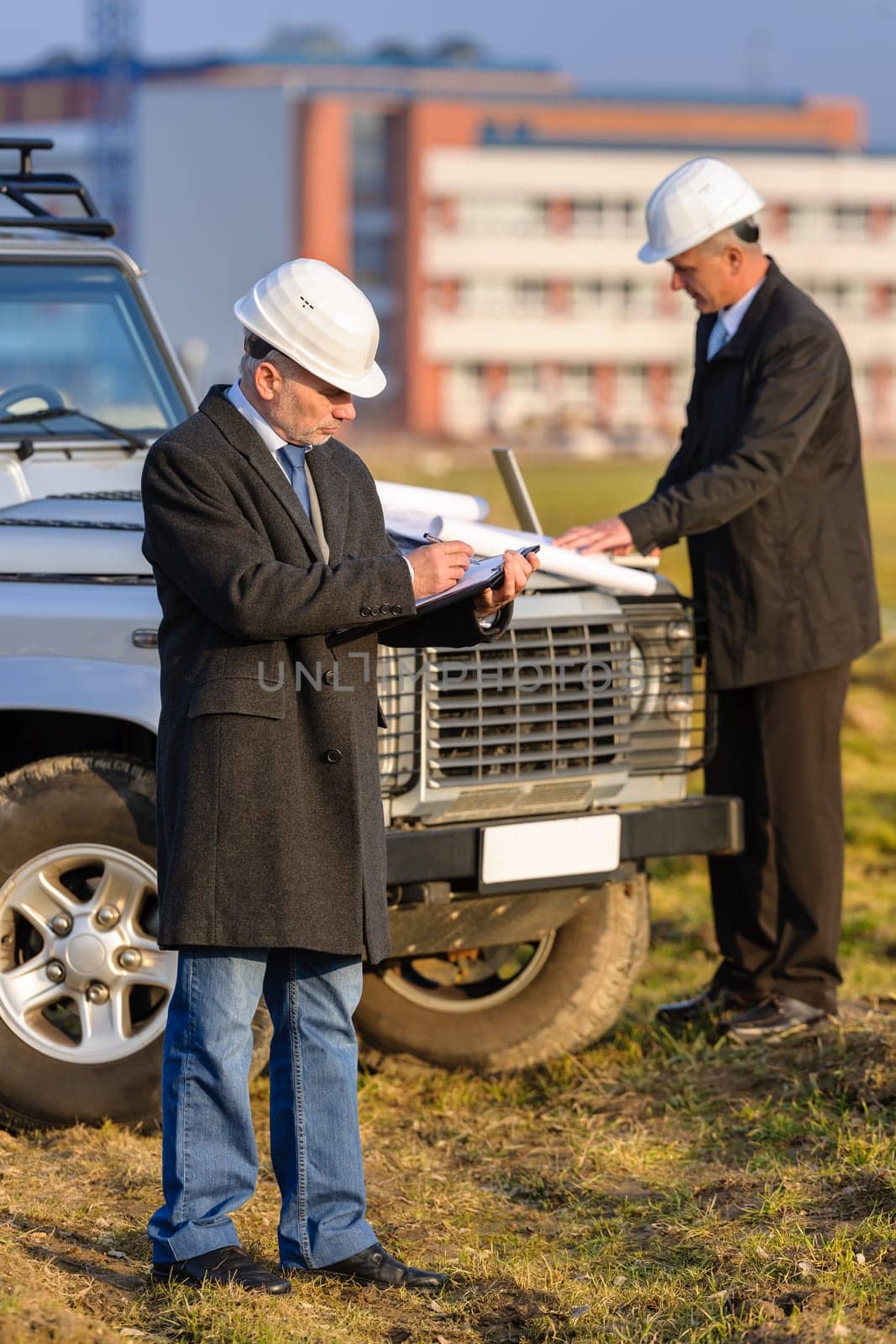 Male architect developers on construction site making notes building project