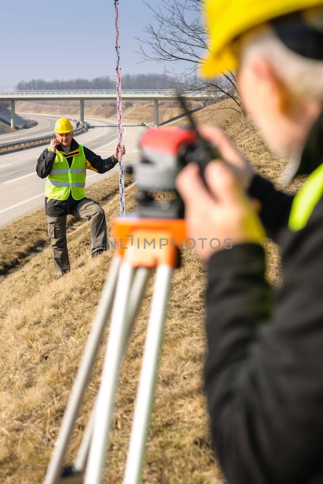 Land surveyors on highway measuring with theodolite
