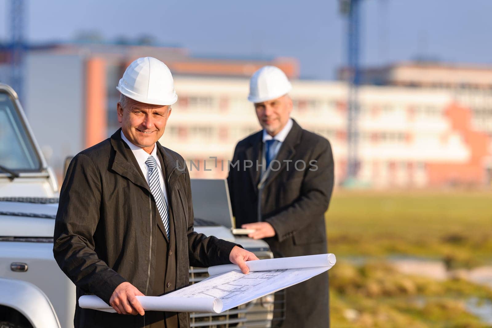 Two architect developers reviewing building plans at construction site