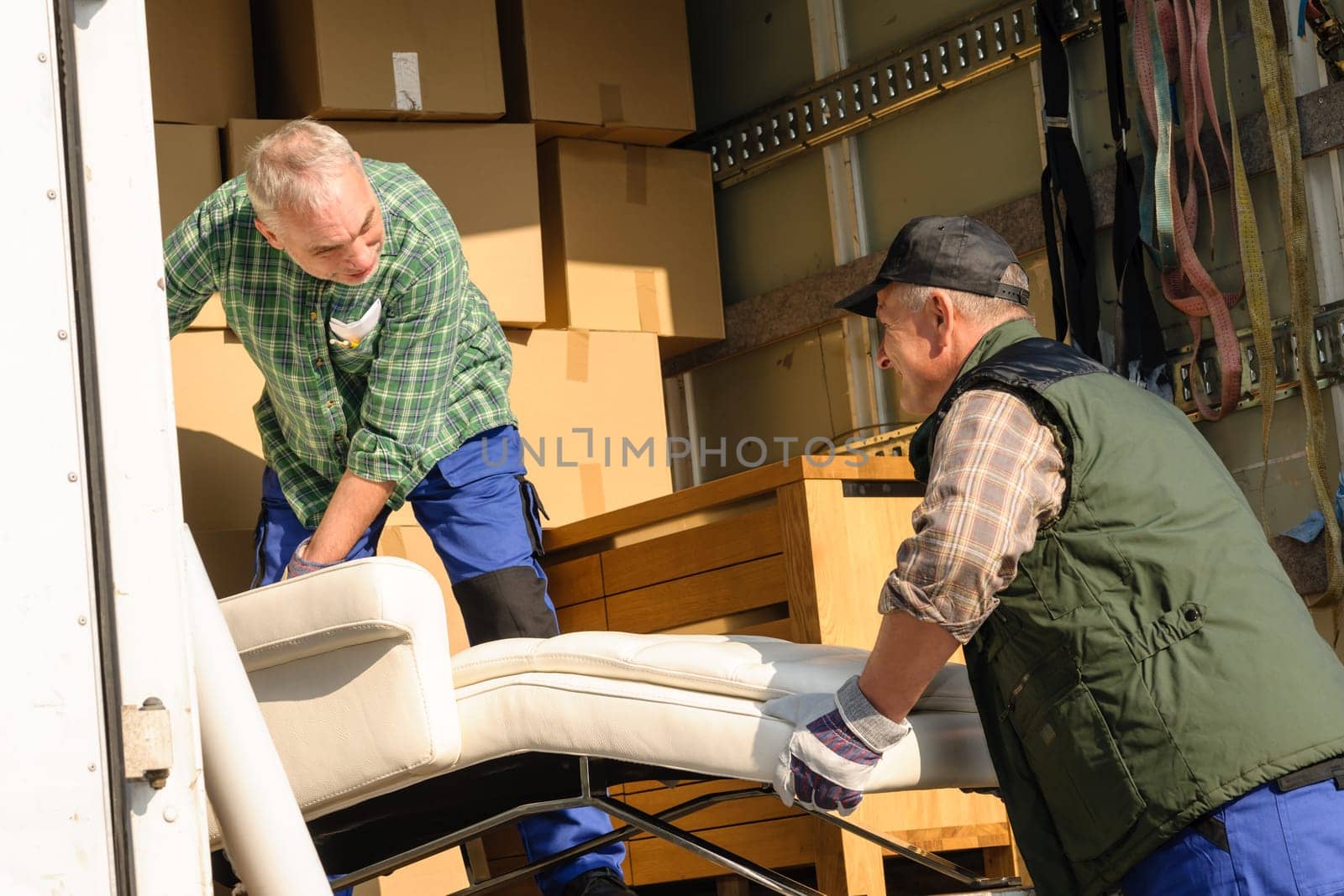 Two male movers putting furniture and boxes in moving truck