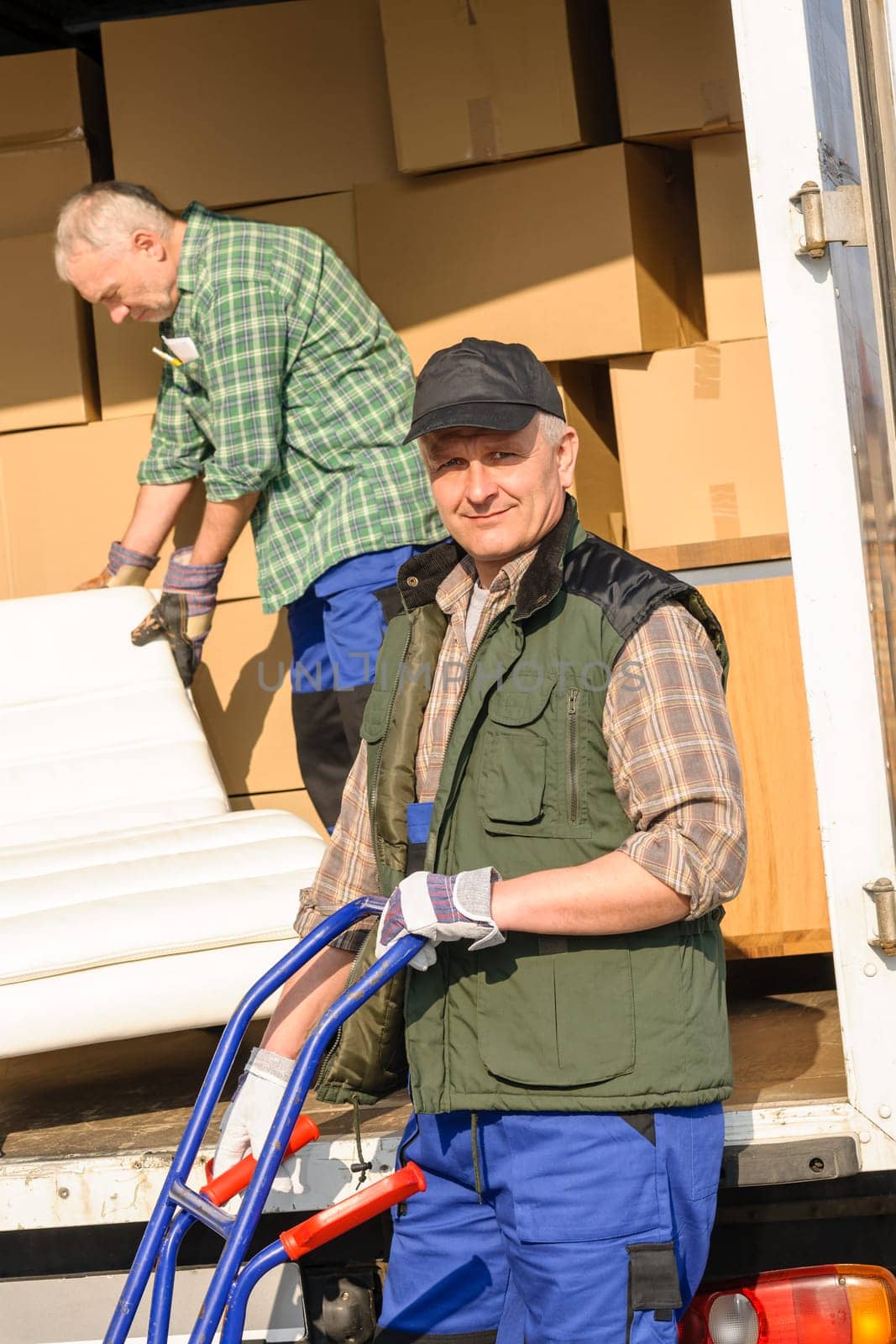 Two movers man loading furniture and boxes from truck vehicle