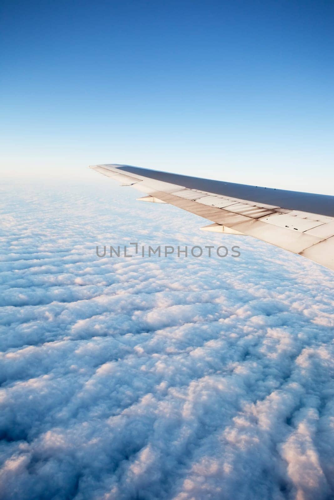 A wing of an airplane flying of a cloudscape