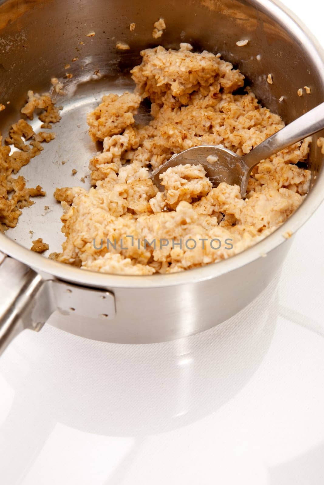 A pot of old cold porridge on a reflective white background