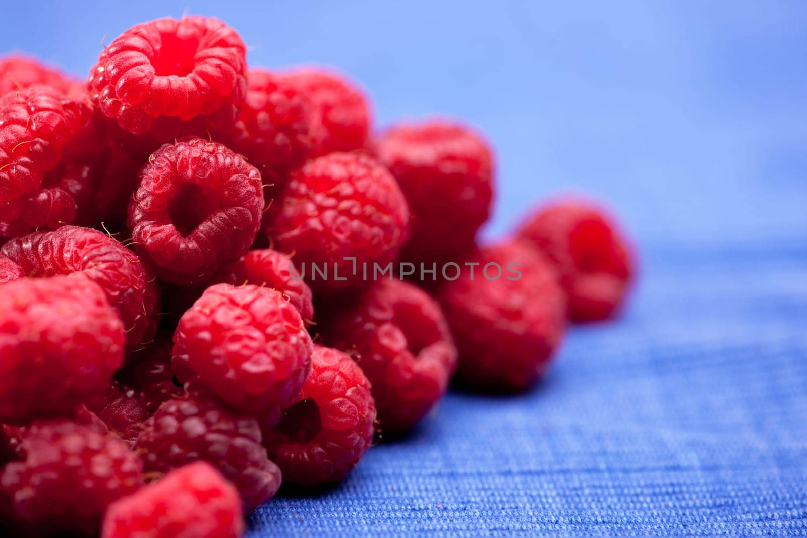 Fresh raspberries isolated on a blue cloth