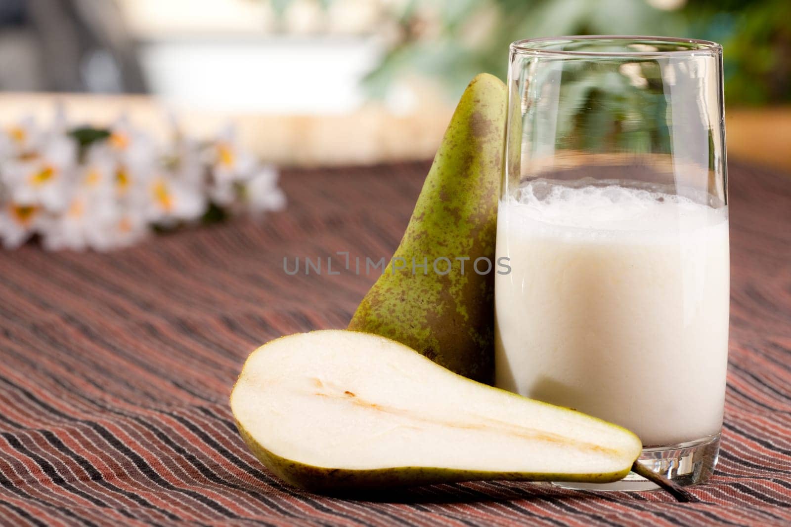 A tall glass of pear smoothie in a natural setting