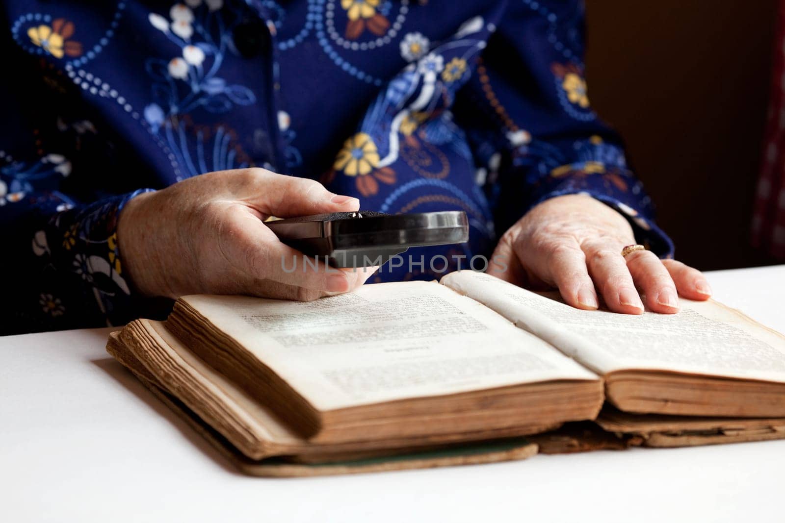 An elderly woman reading a very old book