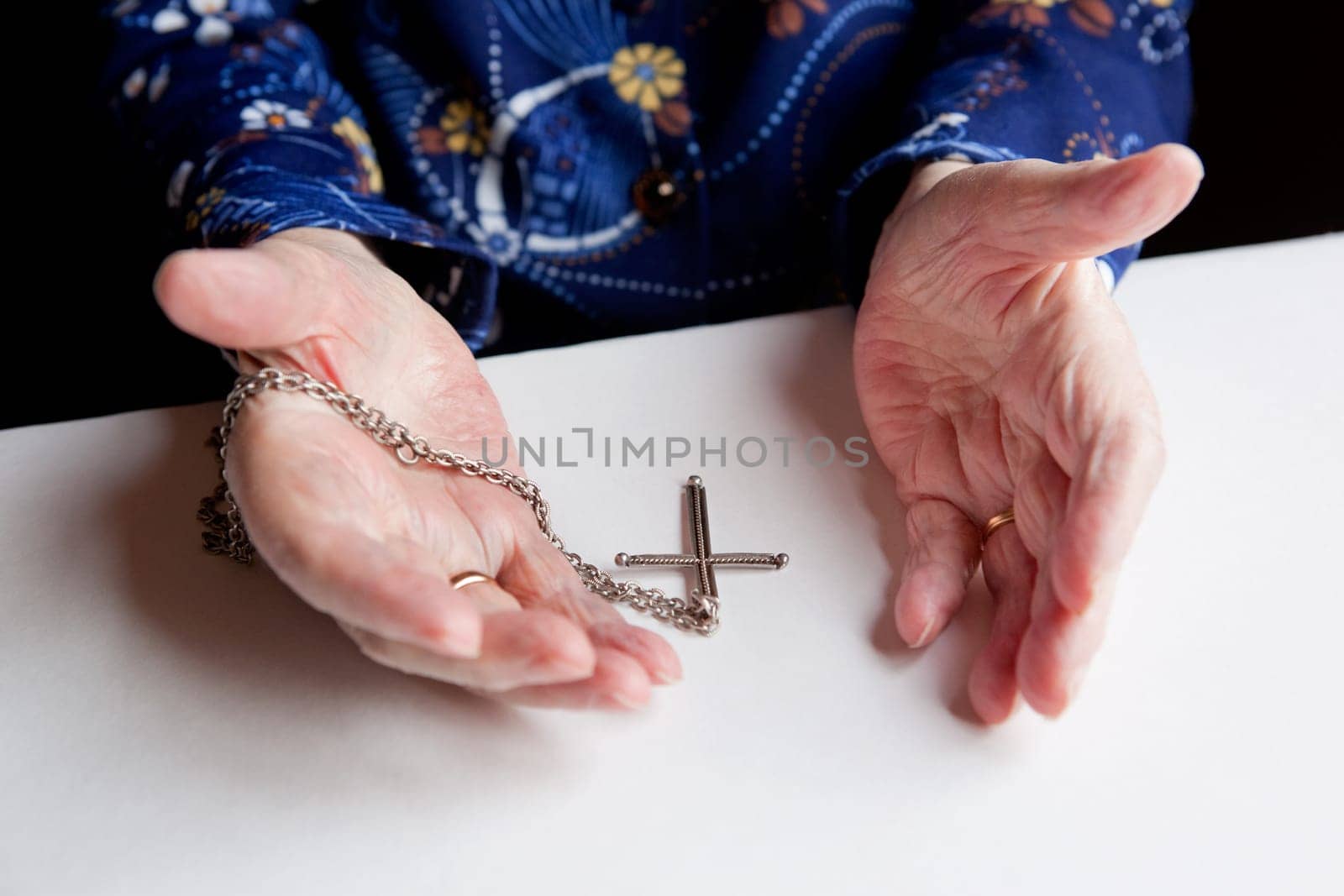 A pair of old hands and a cross - shallow depth of field with focus on the cross