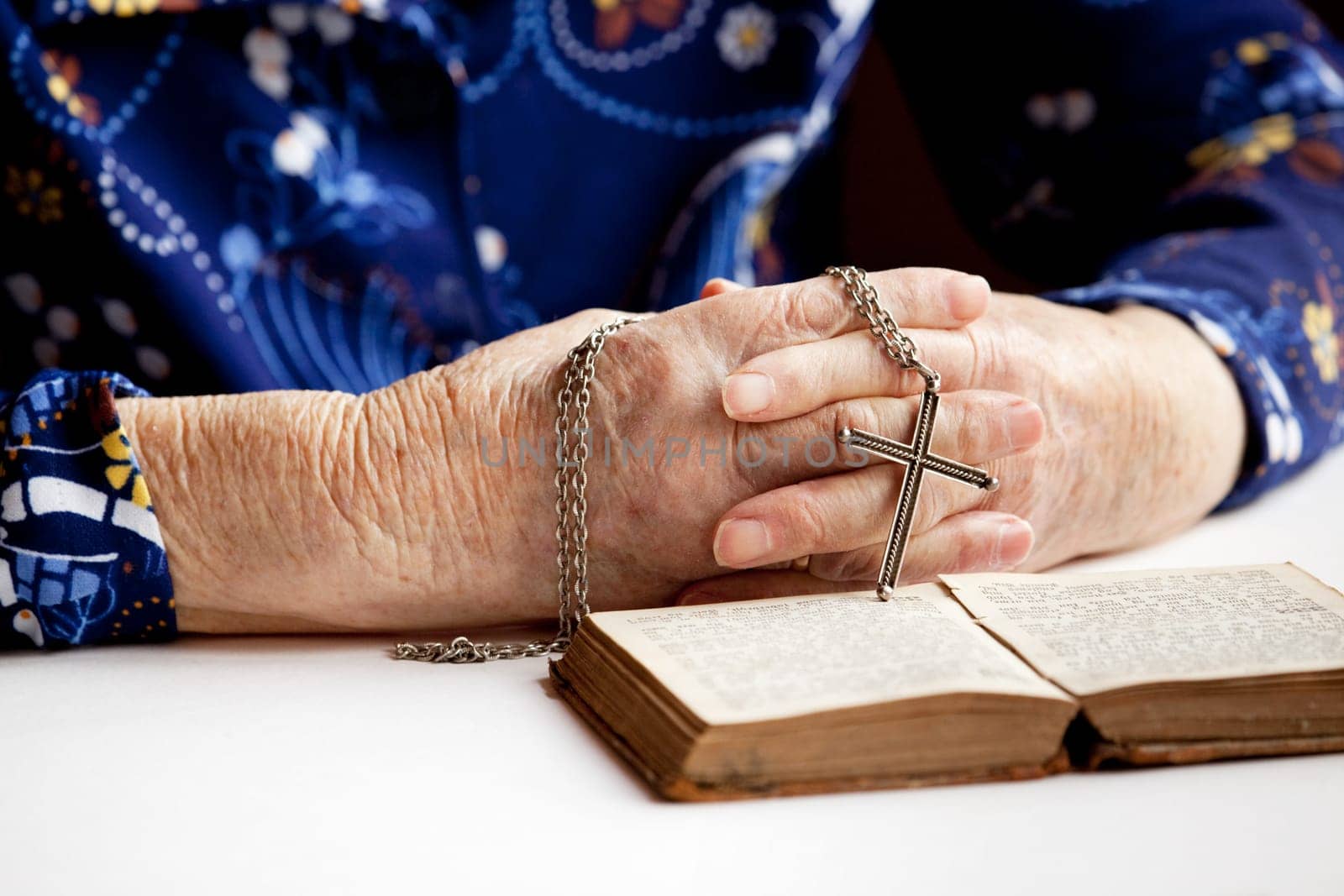 An elderly pair of hands holding a cross