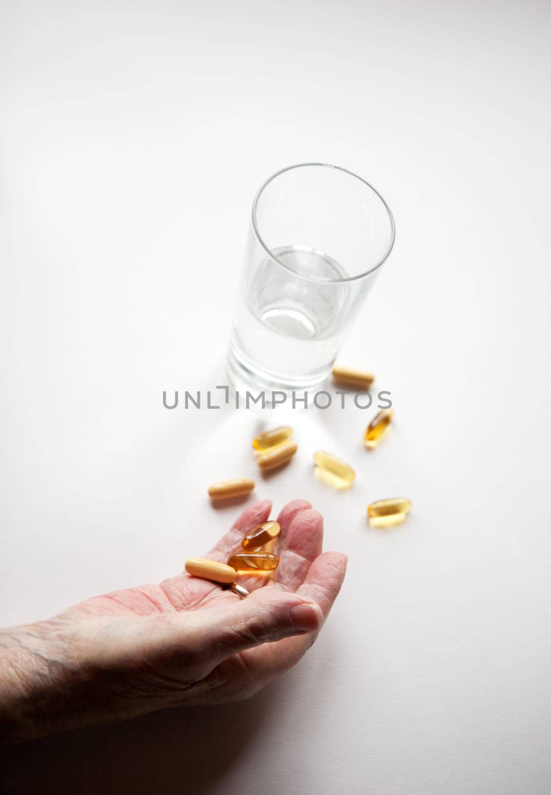 An elderly hand with a variety of large pills - shallow depth of field, focus on hand and pills