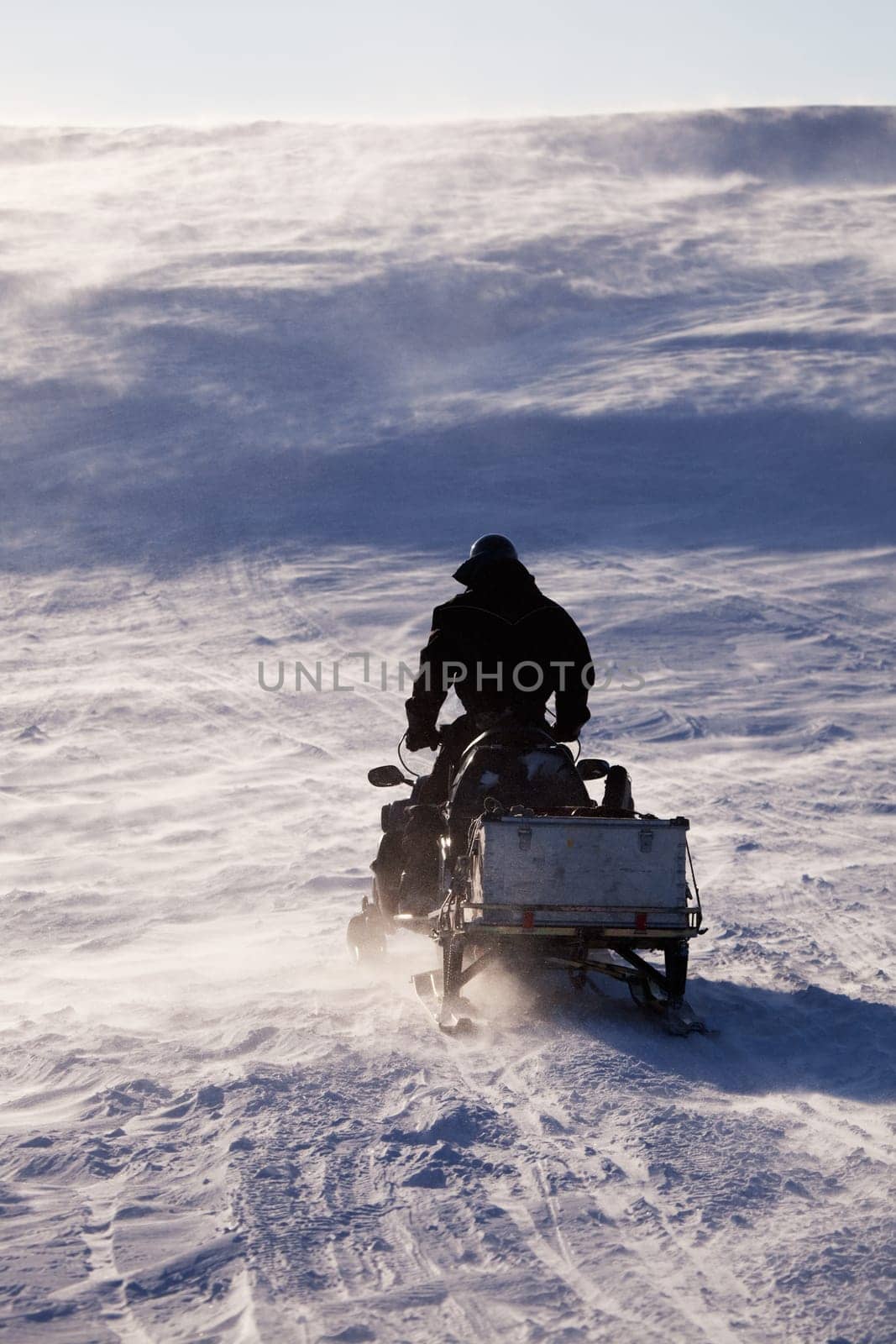 A man sitting on a snowmobile on a barren snow landscape