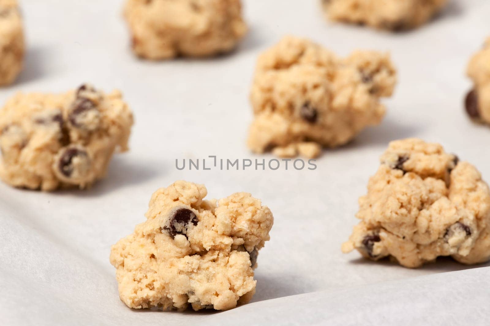 Raw cookie dough on a baking sheet with parchment